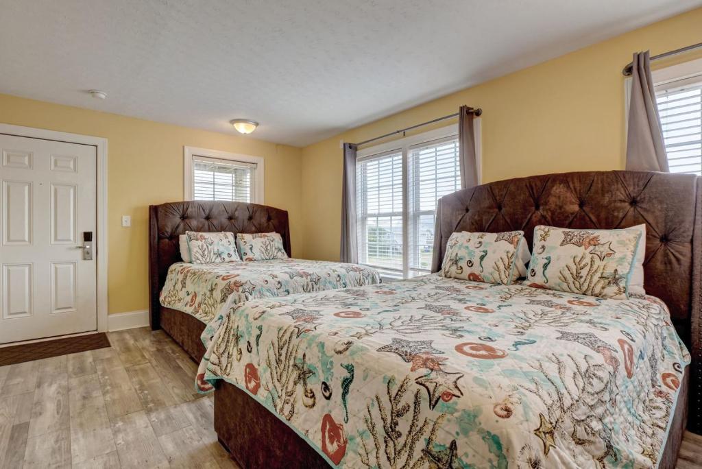 two beds in a bedroom with yellow walls at Unit 112D at Tiffany's in Surf City