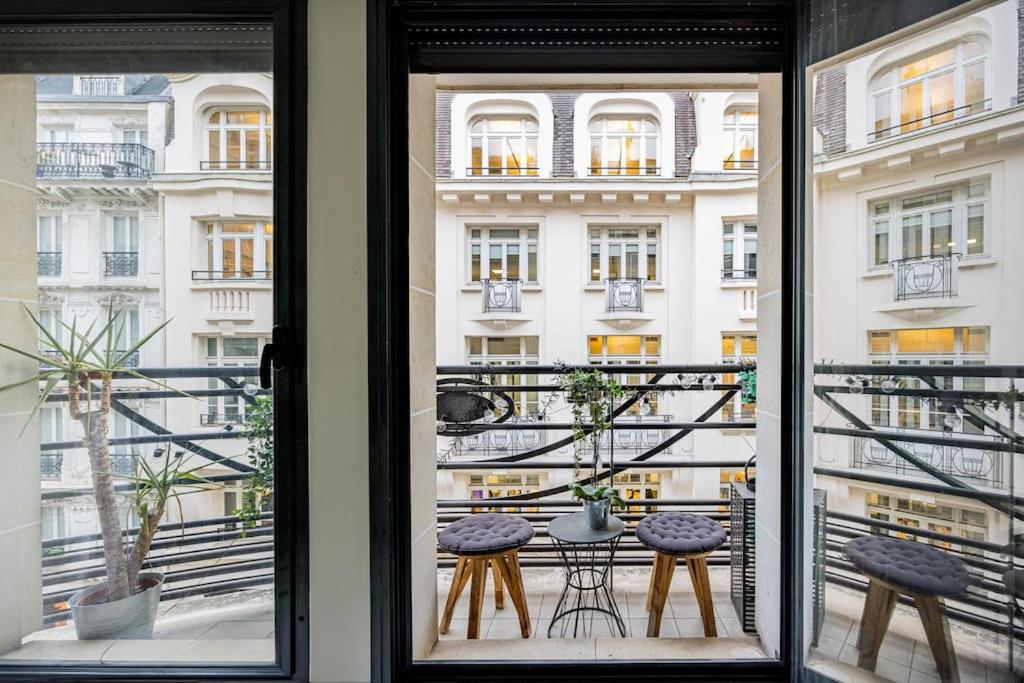 Cette chambre dispose d'une fenêtre donnant sur un balcon avec une table et des chaises. dans l'établissement Grand et central, 8e près Élysée, à Paris