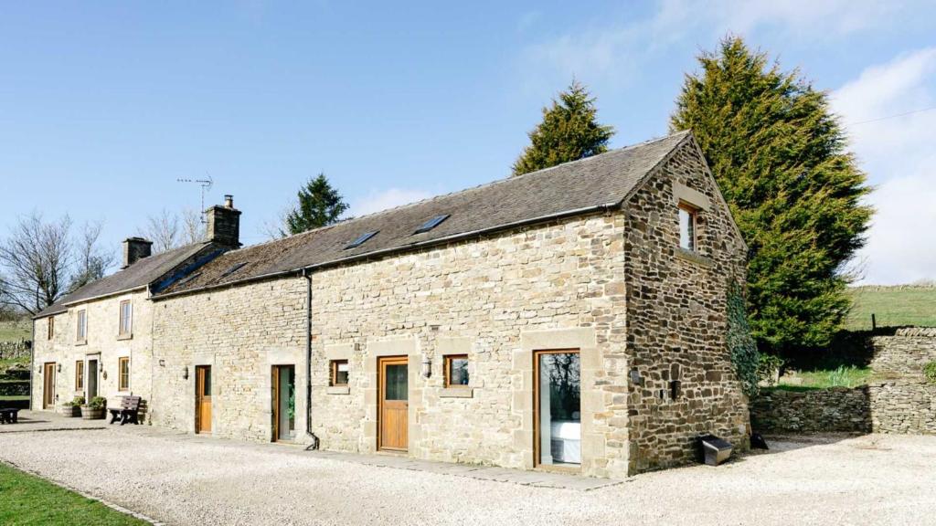 an old stone building with orange doors and windows at Lapwing Barns in Longnor