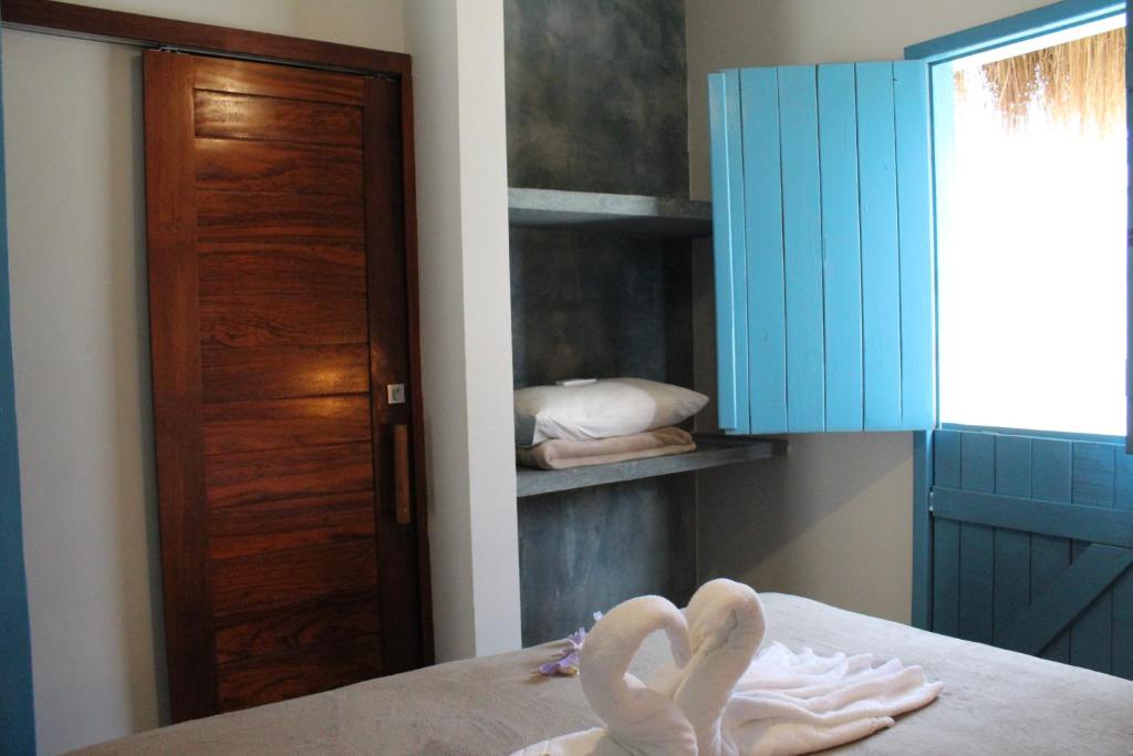 two towels on a bed in a room with a door at Pousada Vila Lua Bela in Pitimbu
