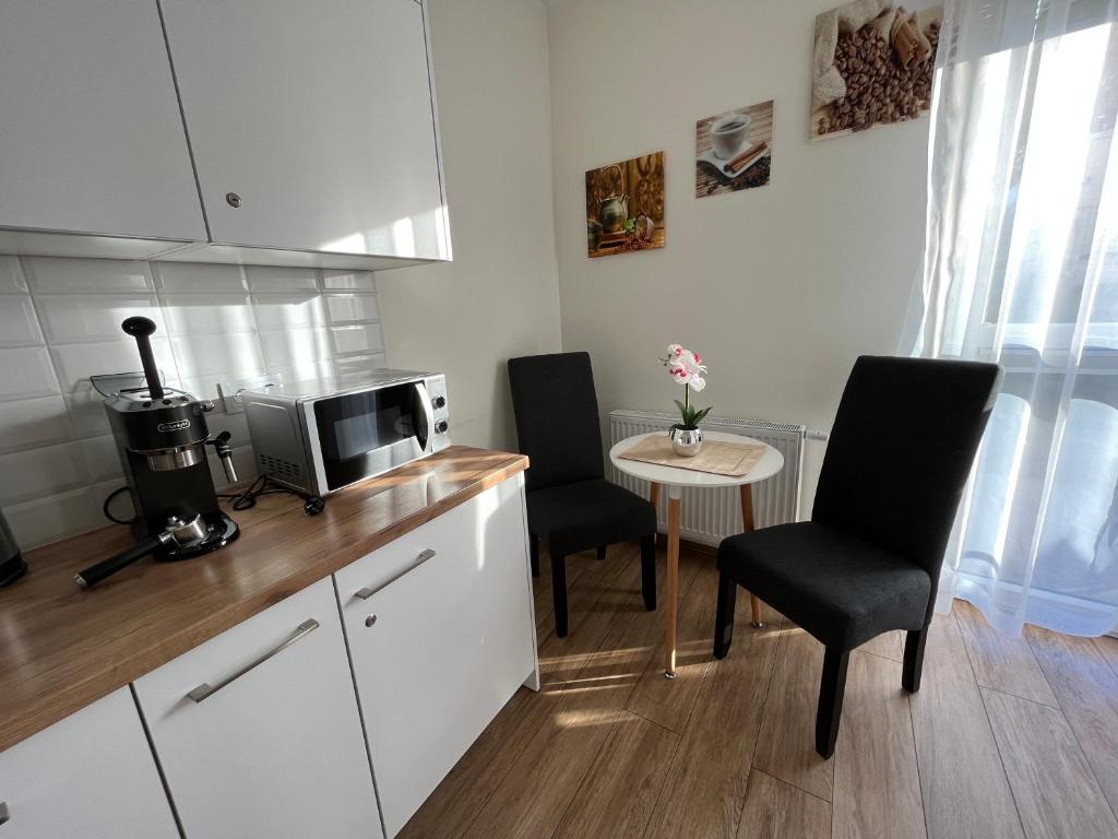 una cocina con 2 sillas y una mesa pequeña en Apartamenty Kielce- Apartament Zacisze przy Baseny Tropikalne, Kadzielnia, parking, faktura en Kielce