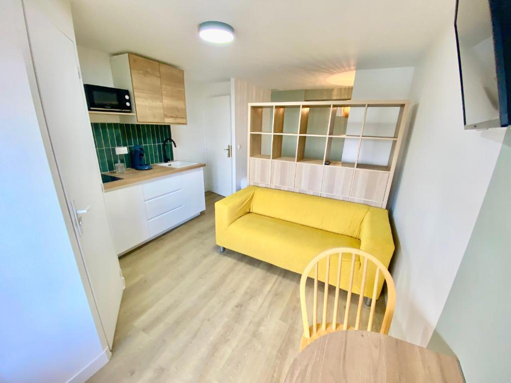 salon z żółtą kanapą i kuchnią w obiekcie L'Escale Appartements et Suites en bord de Mer w Hawrze