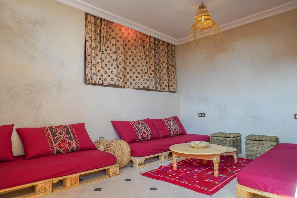 a living room with red couches and a table at SurfAppart Morocco in Tamraght Ouzdar