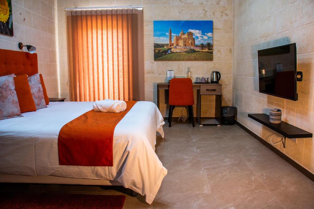Schlafzimmer mit einem Bett, einem Schreibtisch und einem TV in der Unterkunft Sea Holly Gozo in Nadur