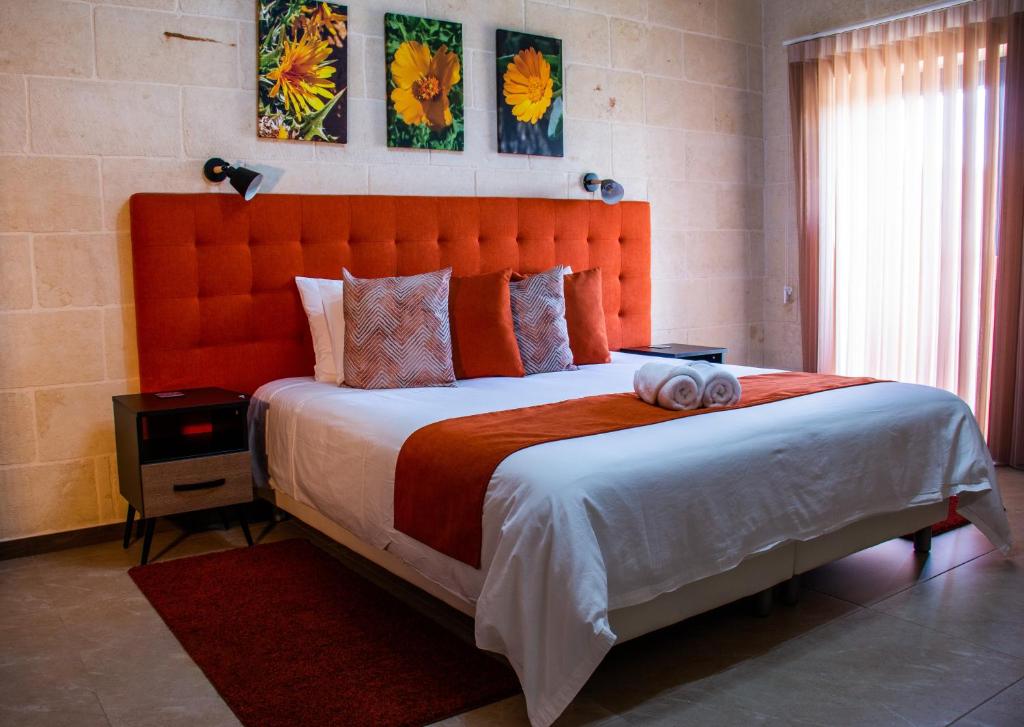 a bedroom with a large bed with an orange headboard at Sea Holly Gozo in Nadur