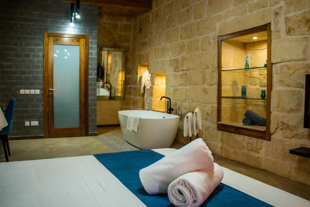 ein Bad mit einer Badewanne, einem Waschbecken und einem Bett in der Unterkunft Sea Holly Gozo in Nadur