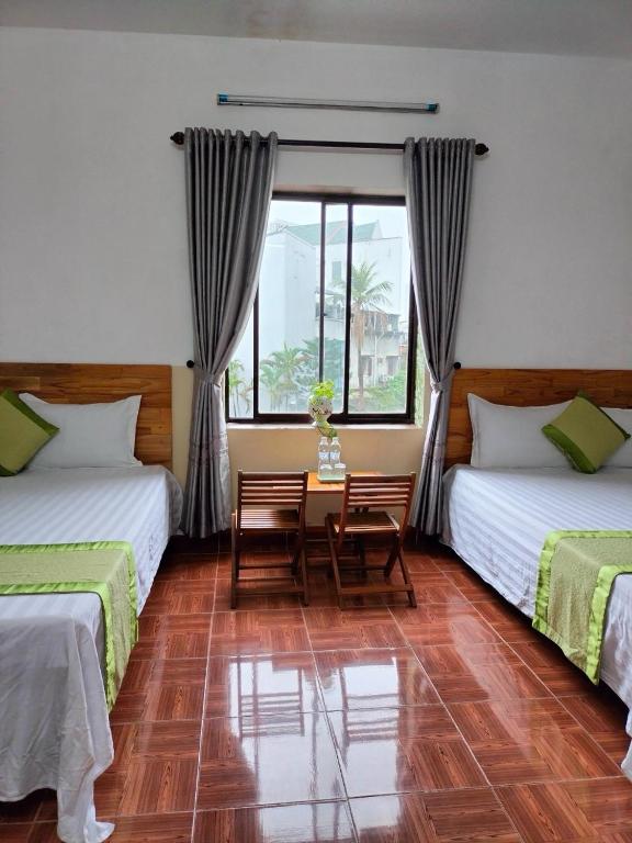 a bedroom with two beds and a table and chairs at RICE HOUSE HUE in Hue