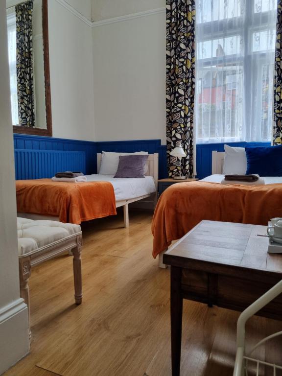 a room with two beds with orange sheets at The Windmill Hotel in London