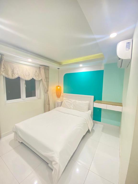 1 dormitorio con cama blanca y pared azul en Khách Sạn Bãi Dâu 178 Trần Phú Vũng Tàu en Vung Tau