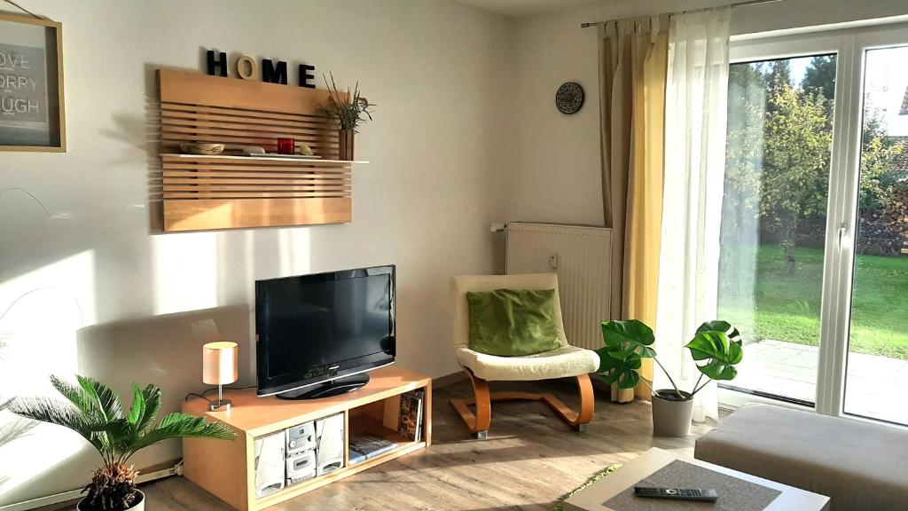 uma sala de estar com uma televisão de ecrã plano e uma cadeira em Ferienwohnungen Geier em Niederalteich