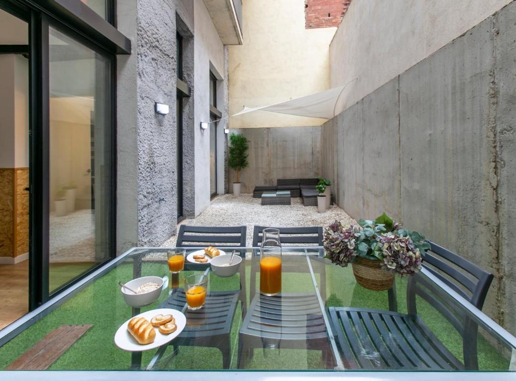 a glass table with plates of food on it on a balcony at 11 Luminous and cozy apartment in Gracia in Barcelona