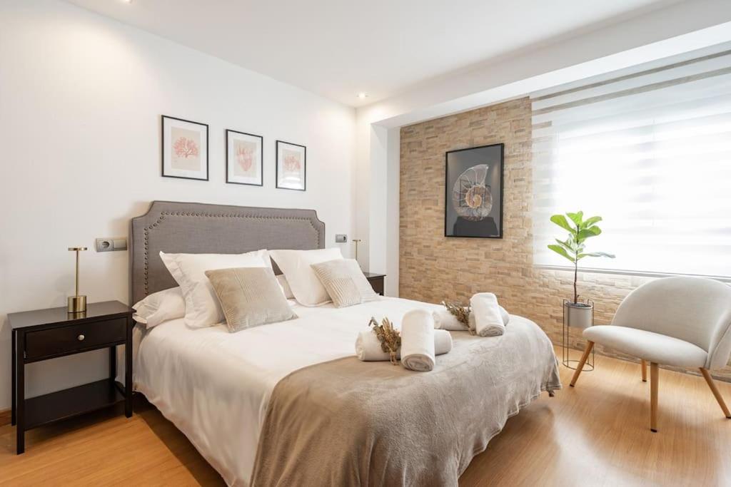 een slaapkamer met een groot wit bed en een stoel bij Escalera 12 in Gijón