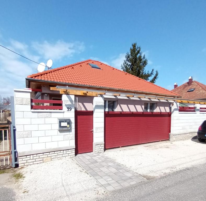 a house with red garage doors on a street at Flower 3 free parking in Siófok