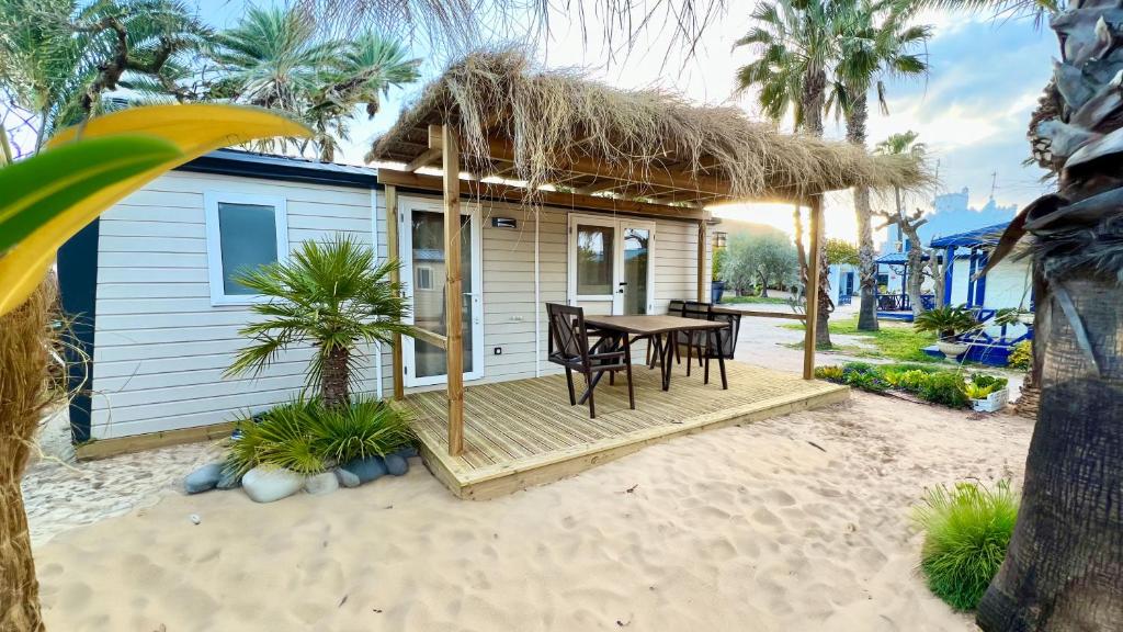 Cámping & Bungalows Estanyet في لي كاز دالكانار: منزل صغير مع طاولة وكراسي على الشاطئ