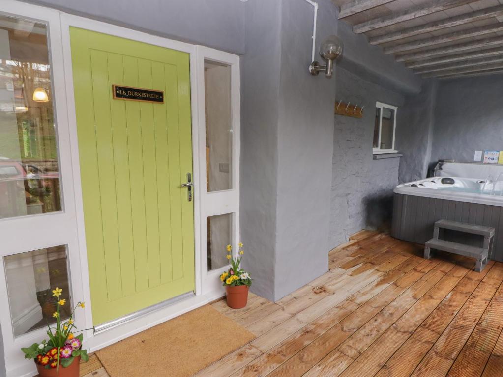 a green door in a bathroom with a tub at Le Durkestrete Cellar in Haverfordwest