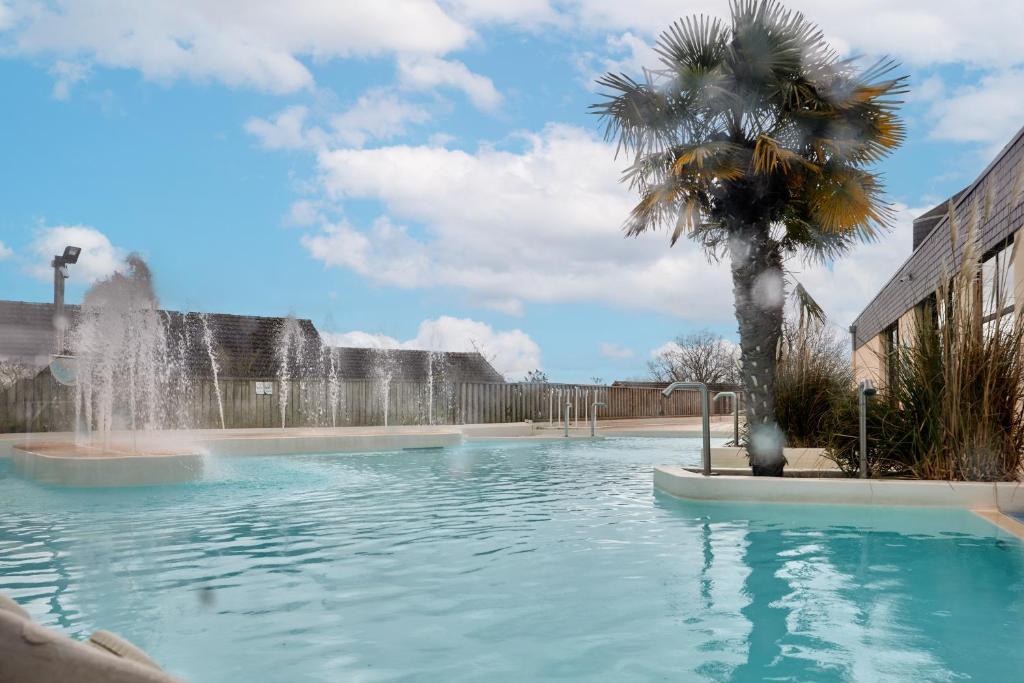 una fuente en una piscina con una palmera en Maison Jade - piscines partagées, en Branville