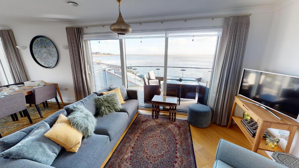 a living room with a blue couch and a large window at The Point in Exmouth