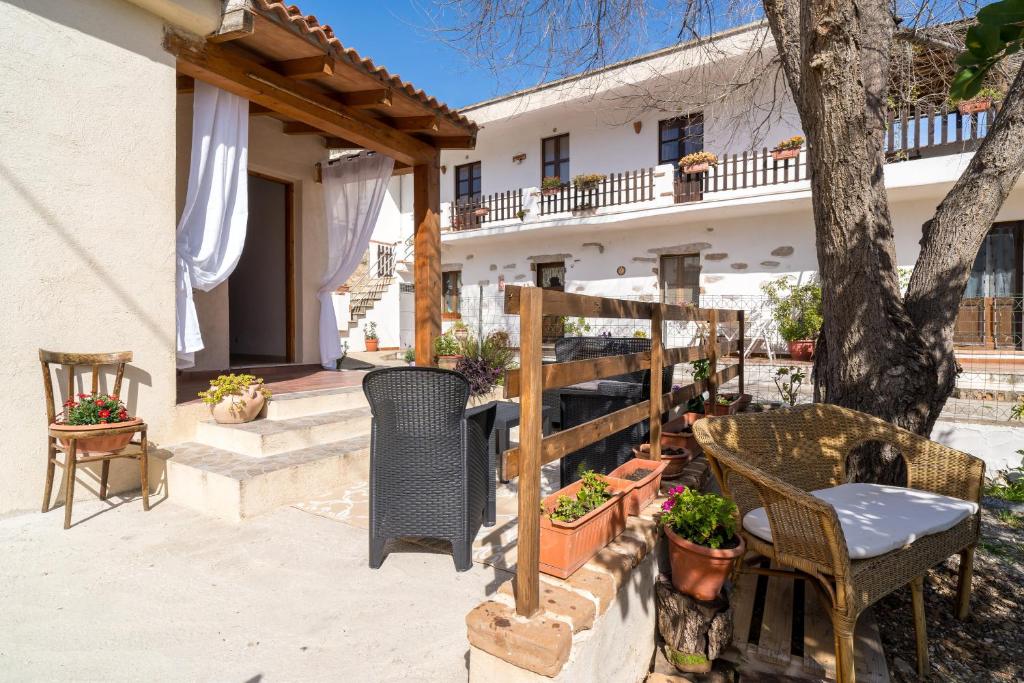 a patio with chairs and a tree in front of a house at Casa Masala Irgoli in Irgoli