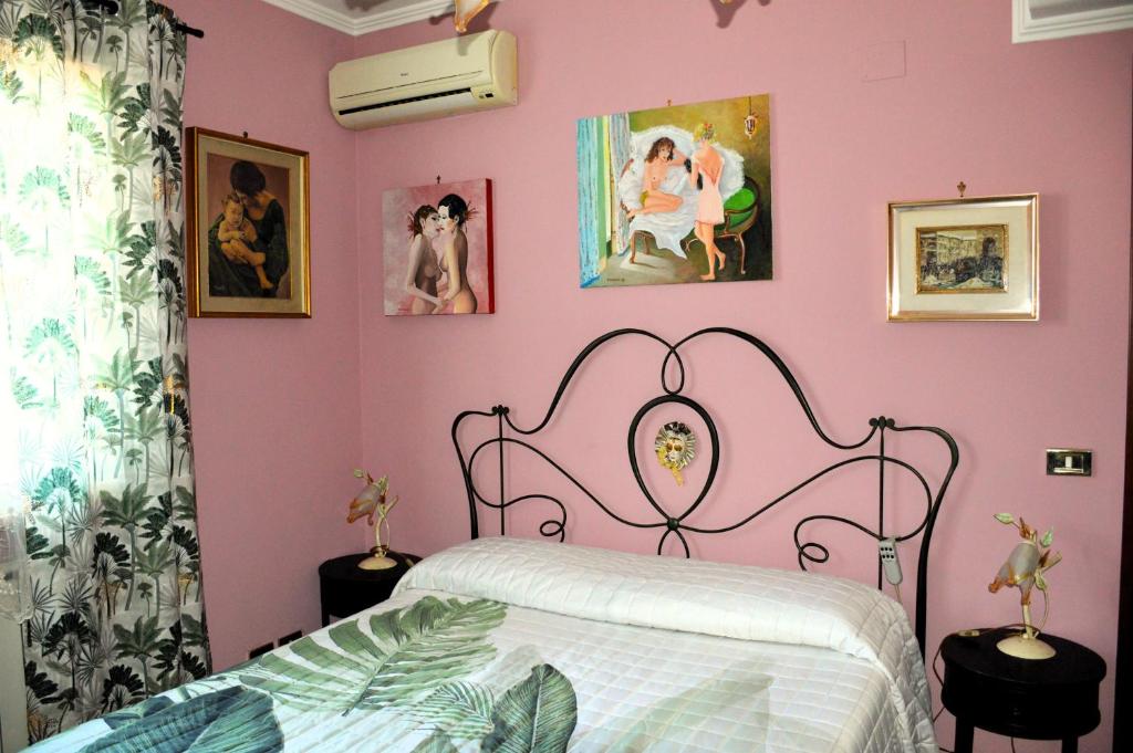 a pink bedroom with a bed and pictures on the wall at L'Oasi delle Vigne in Rome