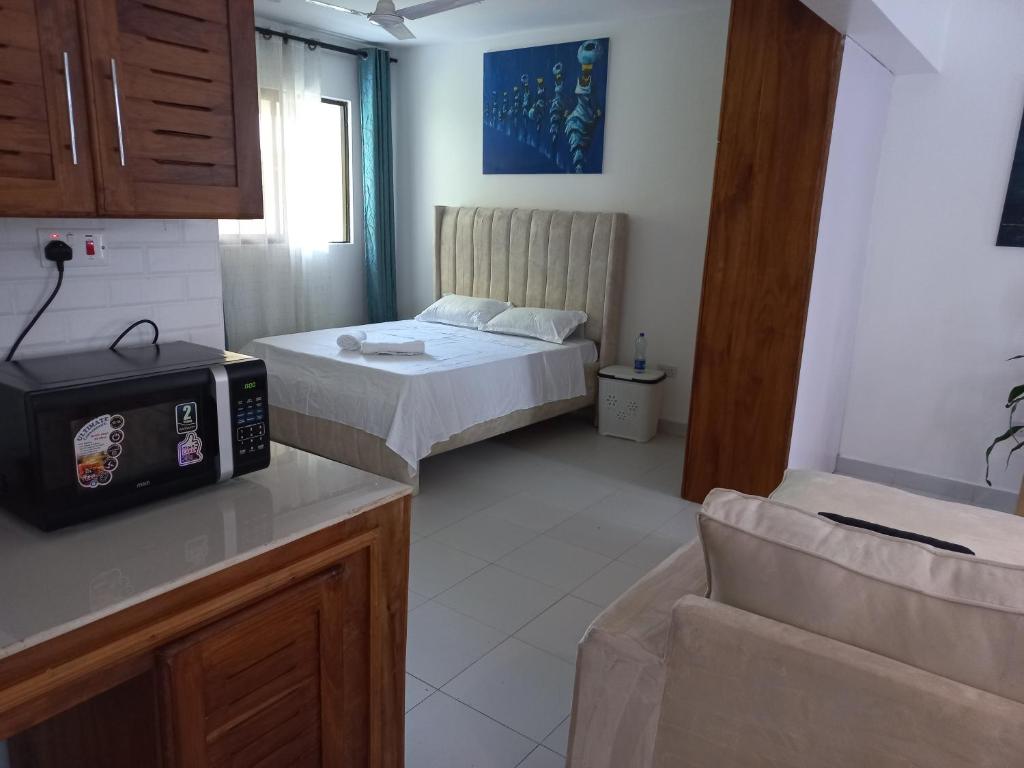 Kleines Zimmer mit 2 Betten und einer Mikrowelle in der Unterkunft Ika homes in Nyali