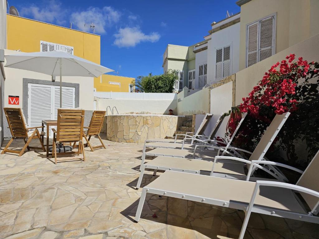 eine Terrasse mit Stühlen, Tischen und einem Sonnenschirm in der Unterkunft Hidden Paradise in San Bartolomé de Tirajana