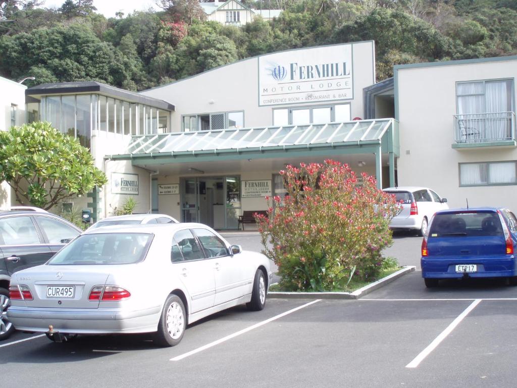 um carro branco estacionado num parque de estacionamento em frente a um edifício em Fernhill Motor Lodge em Lower Hutt