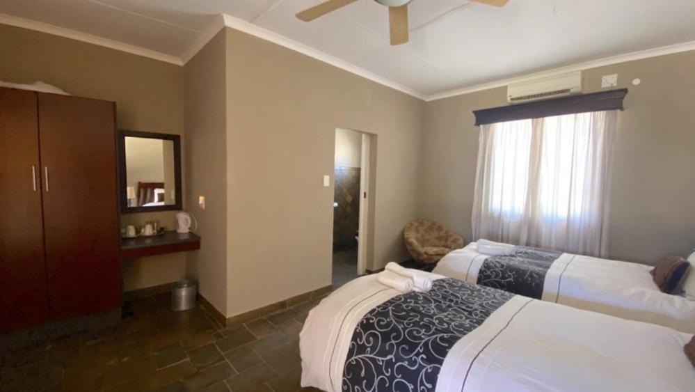 Pokój hotelowy z 2 łóżkami i lustrem w obiekcie Stoney's Country Hotel w mieście Gochas