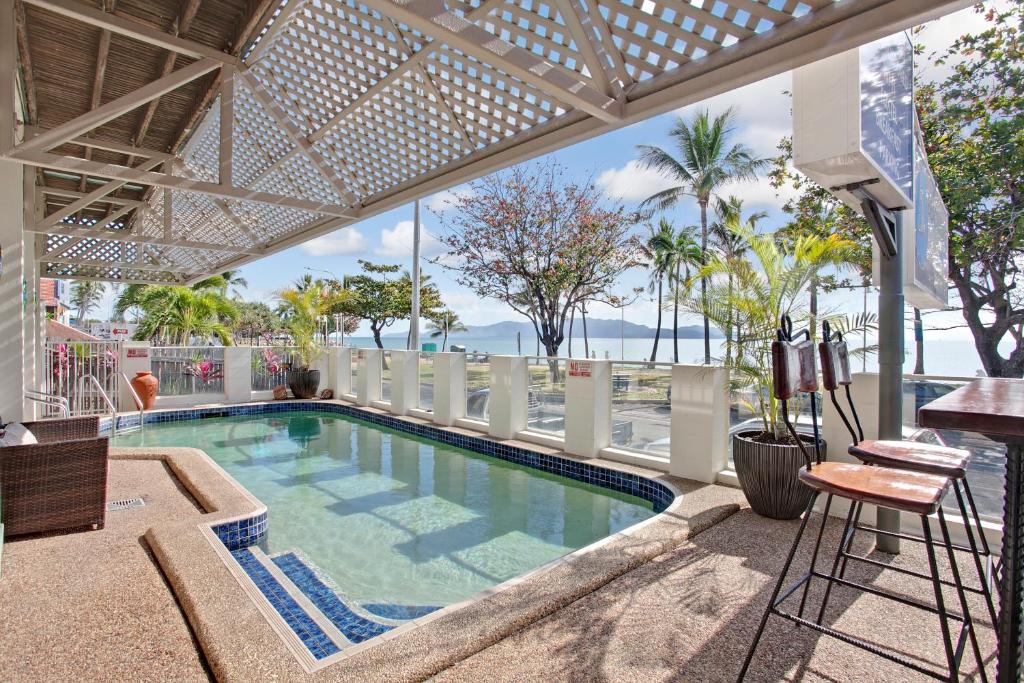 a large swimming pool with a balcony overlooking the ocean at Beach House Motel in Townsville