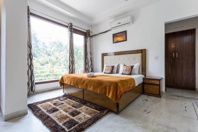a bedroom with a bed and a large window at 1BHK Service Apartment in Nainital