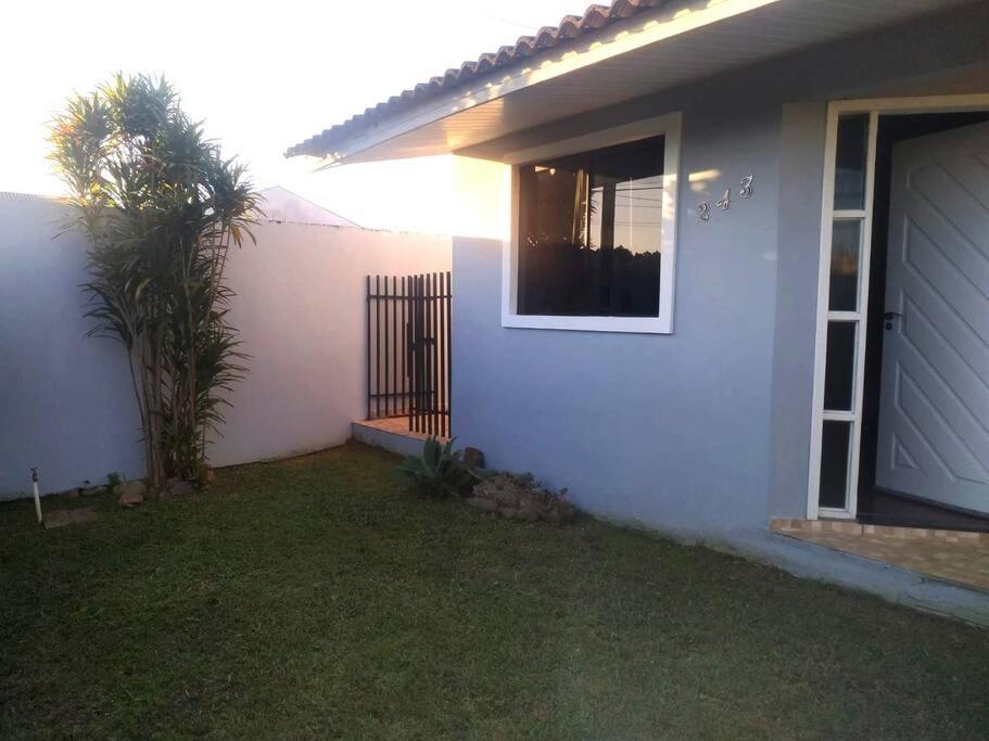 uma casa branca com uma palmeira no quintal em Casa da tia Ju! em São José dos Pinhais