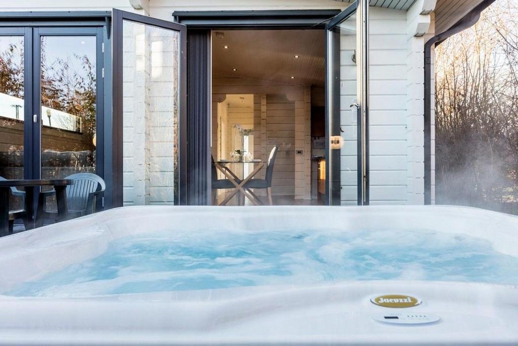 uma grande banheira de hidromassagem em frente a uma casa em Roydon Marina - Lodge 9 - Hot Tub - Pet Friendly em Roydon