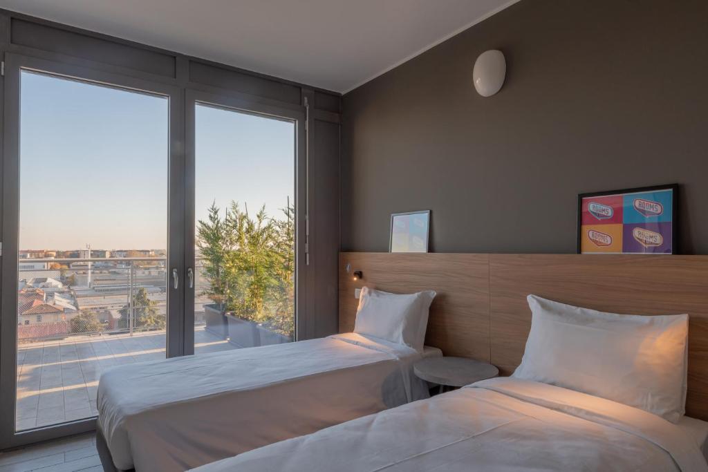 ミラノにあるUnico Studiosのベッド2台と大きな窓が備わるホテルルームです。