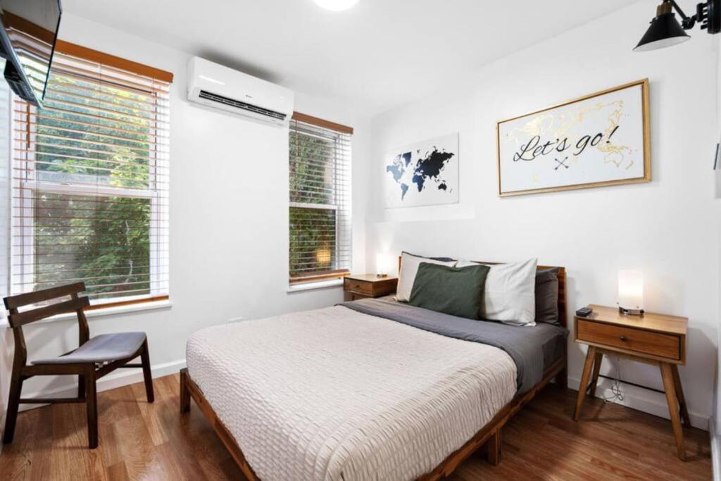 een slaapkamer met een bed, een stoel en ramen bij Sleek Modern 2BR in Bed-Stuy Brooklyn in Brooklyn