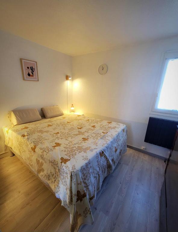 une chambre avec un lit avec un couvre-lit fleuri dans l'établissement Charmant appartement type T2 proche de la mer, au Grau-du-Roi