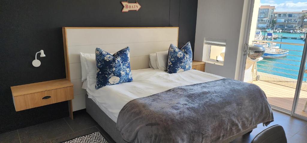 a bedroom with a bed with blue pillows and a window at Sea Breez in St Francis Bay