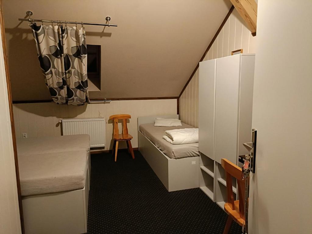 a small room with two beds and a stool at Hotel Kęszyca Leśna in Kęszyca