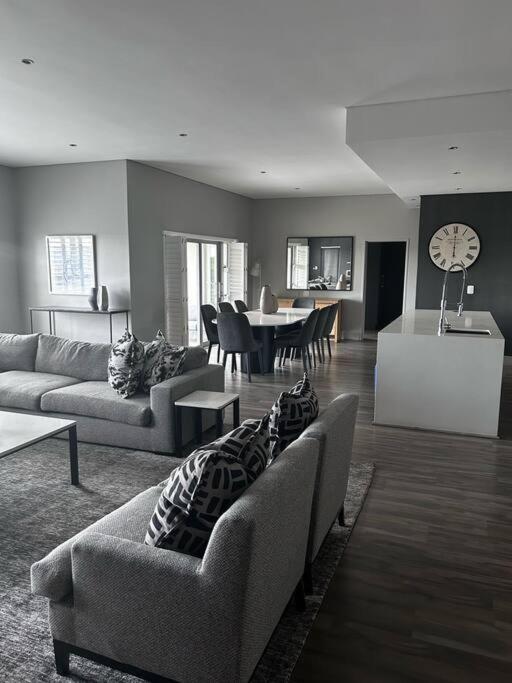 uma sala de estar com 2 sofás e uma sala de jantar em Sandton Penthouse Views & Luxury em Joanesburgo