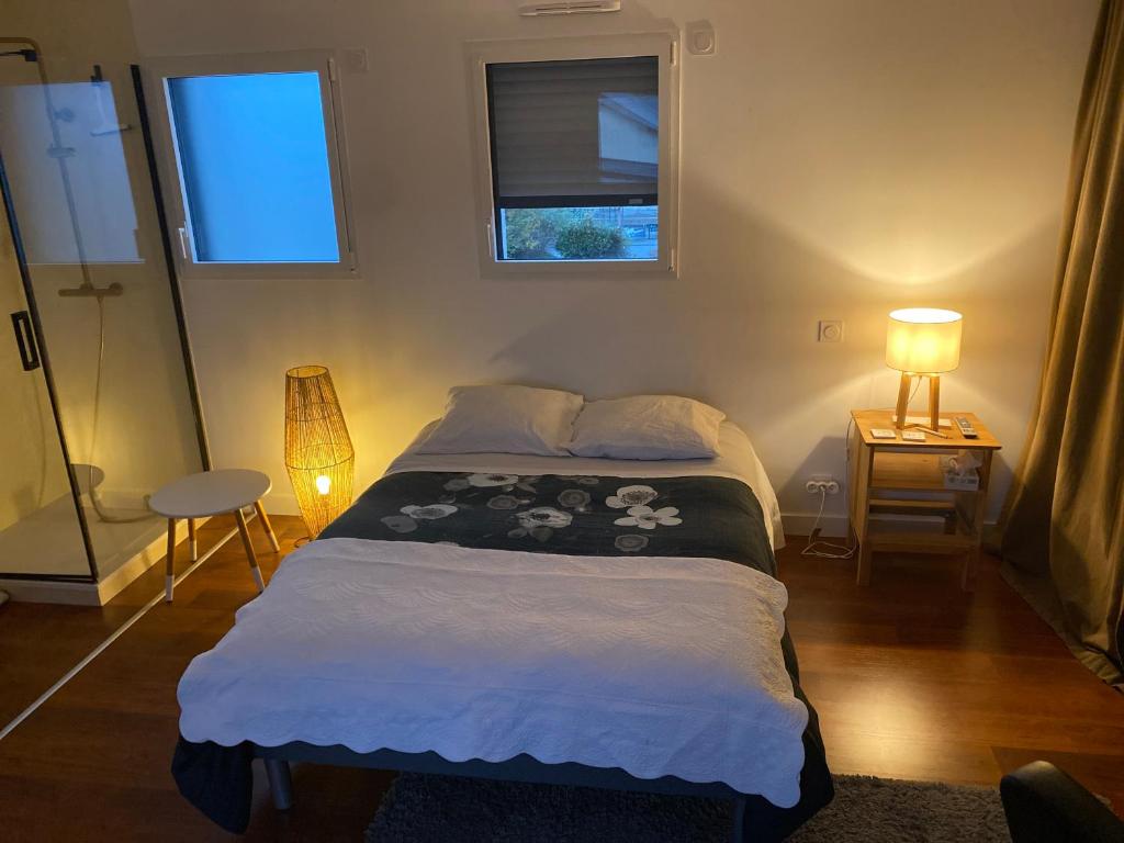 a small bedroom with a bed and two windows at Chambre privé à deux pas de la gare in Montauban-de-Bretagne