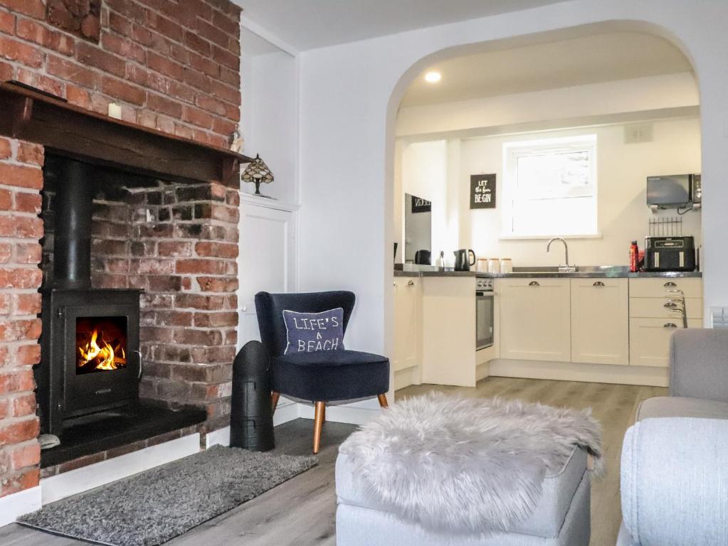 a living room with a brick fireplace and a chair at Henllys in Harlech