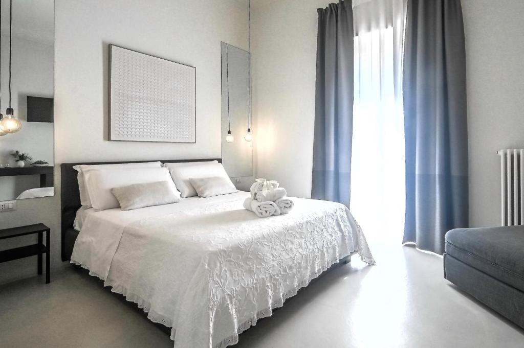 um quarto branco com um urso de peluche sentado numa cama em 42 Zanardelli B&B em Trani