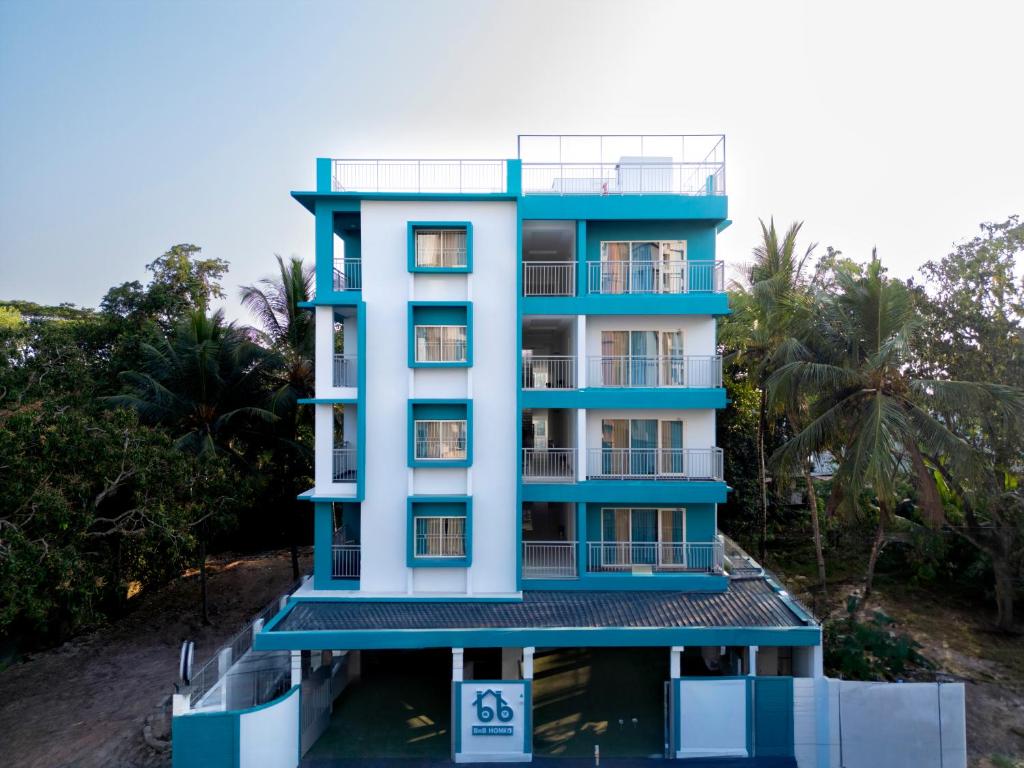 - un bâtiment bleu avec un balcon et des palmiers dans l'établissement BnB Homes, Technopark, Trivandrum, à Kazhakuttam