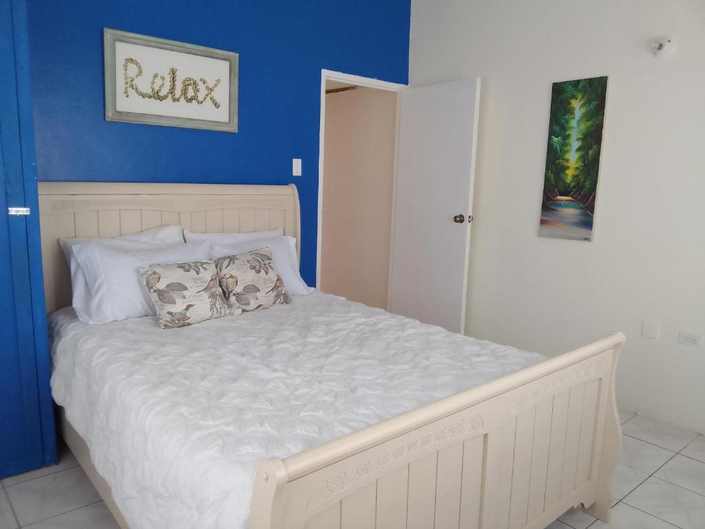 1 dormitorio con cama blanca y pared azul en 1 Queen Bedroom At Csompó Empire, en Saint Mary