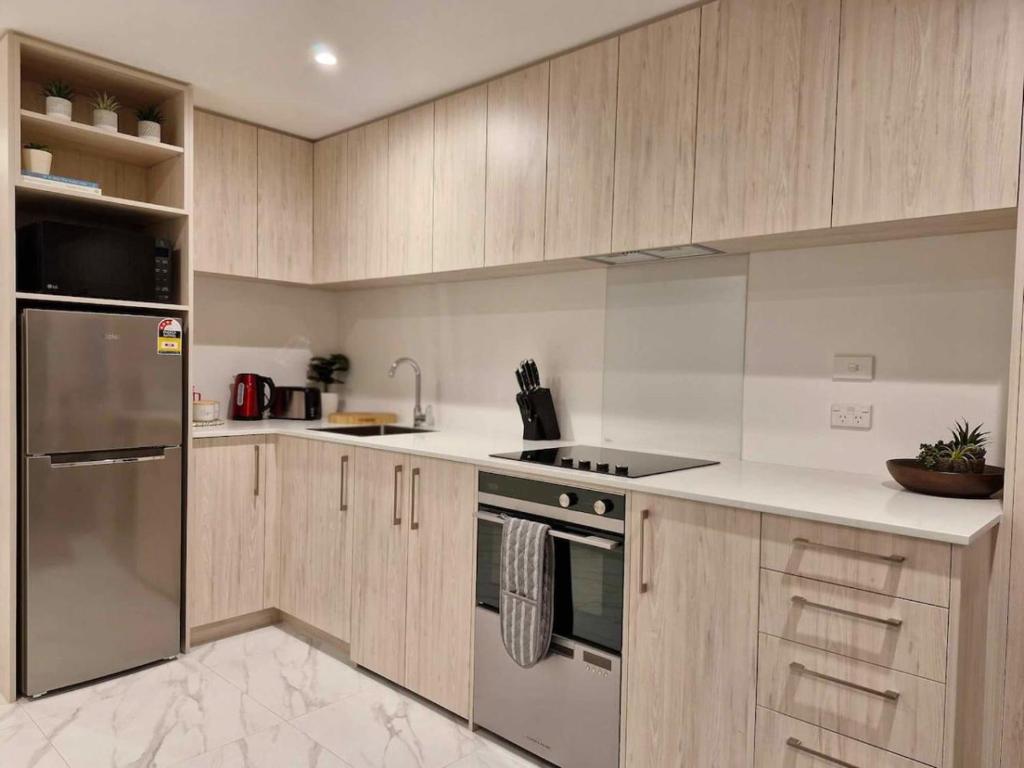 a kitchen with wooden cabinets and stainless steel appliances at Cosy CBD Studio Apartment 6 in Christchurch