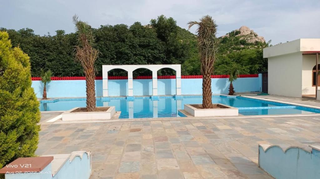 a pool at a resort with two palm trees at Braj samode resort in Sāmod