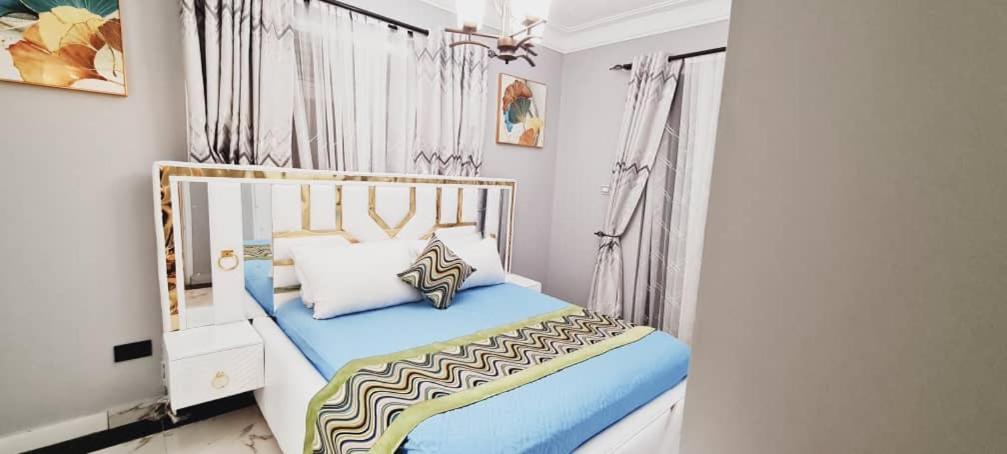 ein Schlafzimmer mit einem großen Bett mit blauer Bettwäsche in der Unterkunft The Crib in Munyonyo in Kampala