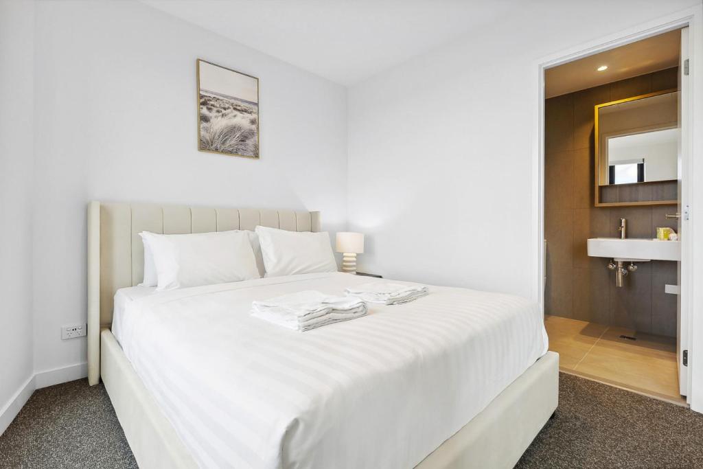 een slaapkamer met een wit bed en een wastafel bij Vibrant Southbank 2 bedroom Apartment in Melbourne