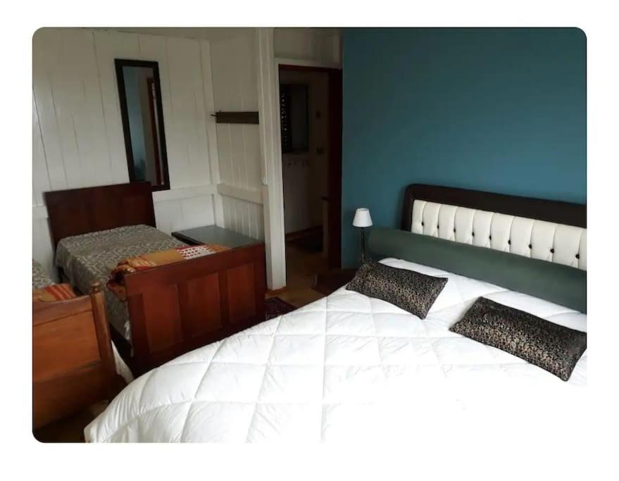 a bedroom with a white bed and a blue wall at Vista da montanha. Casa inteira 6 pessoas. in Barracão