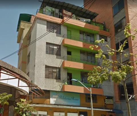 a tall building with green and brown windows at Hotel Estacion San Antonio in Medellín