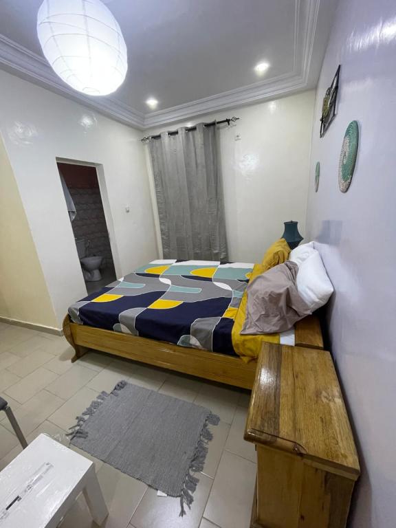 sypialnia z łóżkiem i drewnianym stołem w obiekcie Grand yoff 1 w mieście Ziguinchor