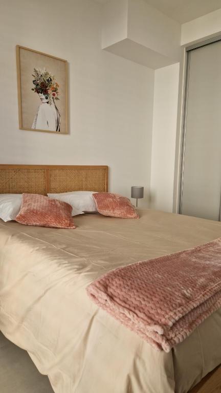 uma cama grande com duas almofadas em cima em Le Malakoff em Sérignan